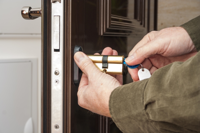 Person replacing a brass door lock cylinder.